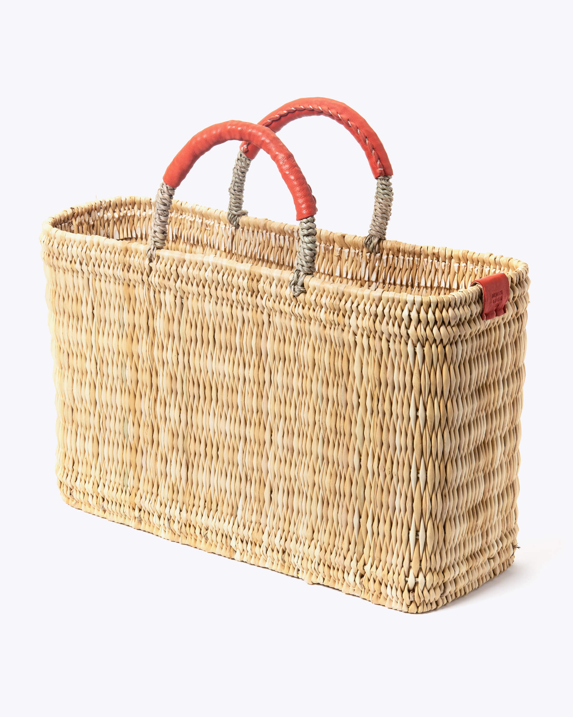 medium straw basket wrapped with orange leather handle on a white background at an angle