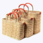 small, medium, large straw basket wrapped with orange leather handles on white background