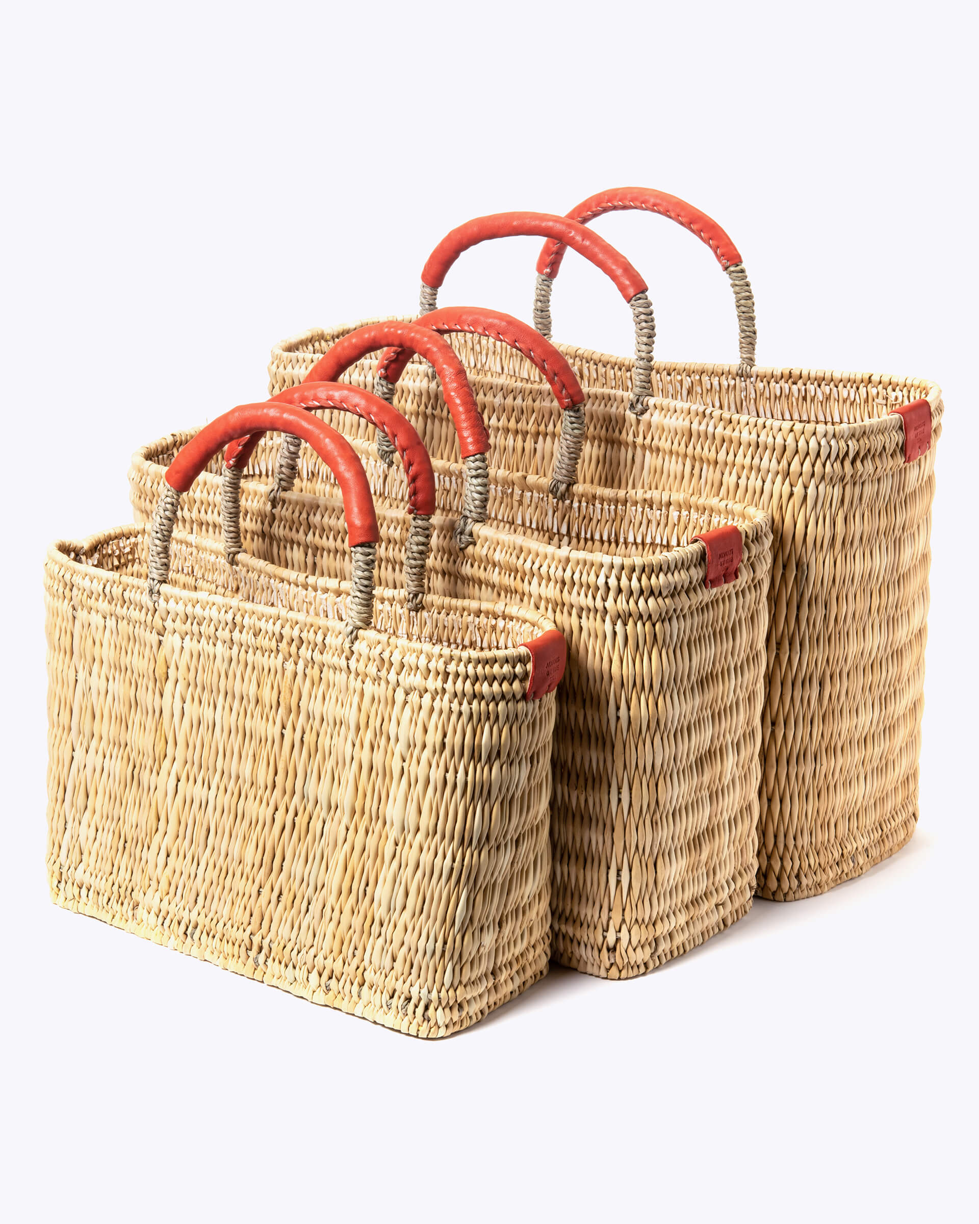 small, medium, large straw basket wrapped with orange leather handles on white background