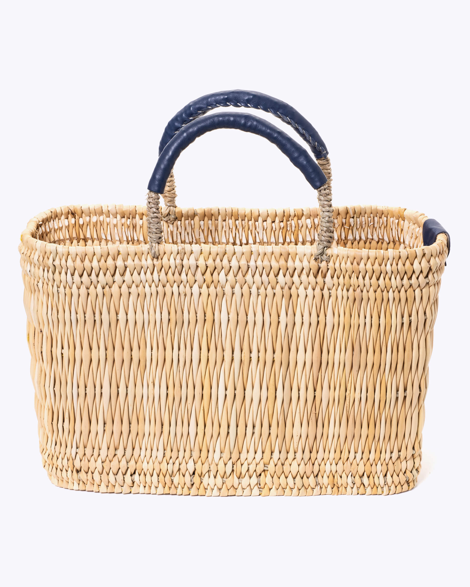 small straw basket wrapped with dark blue leather handle on a white background 