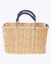 small straw basket wrapped with dark blue leather handle on a white background 
