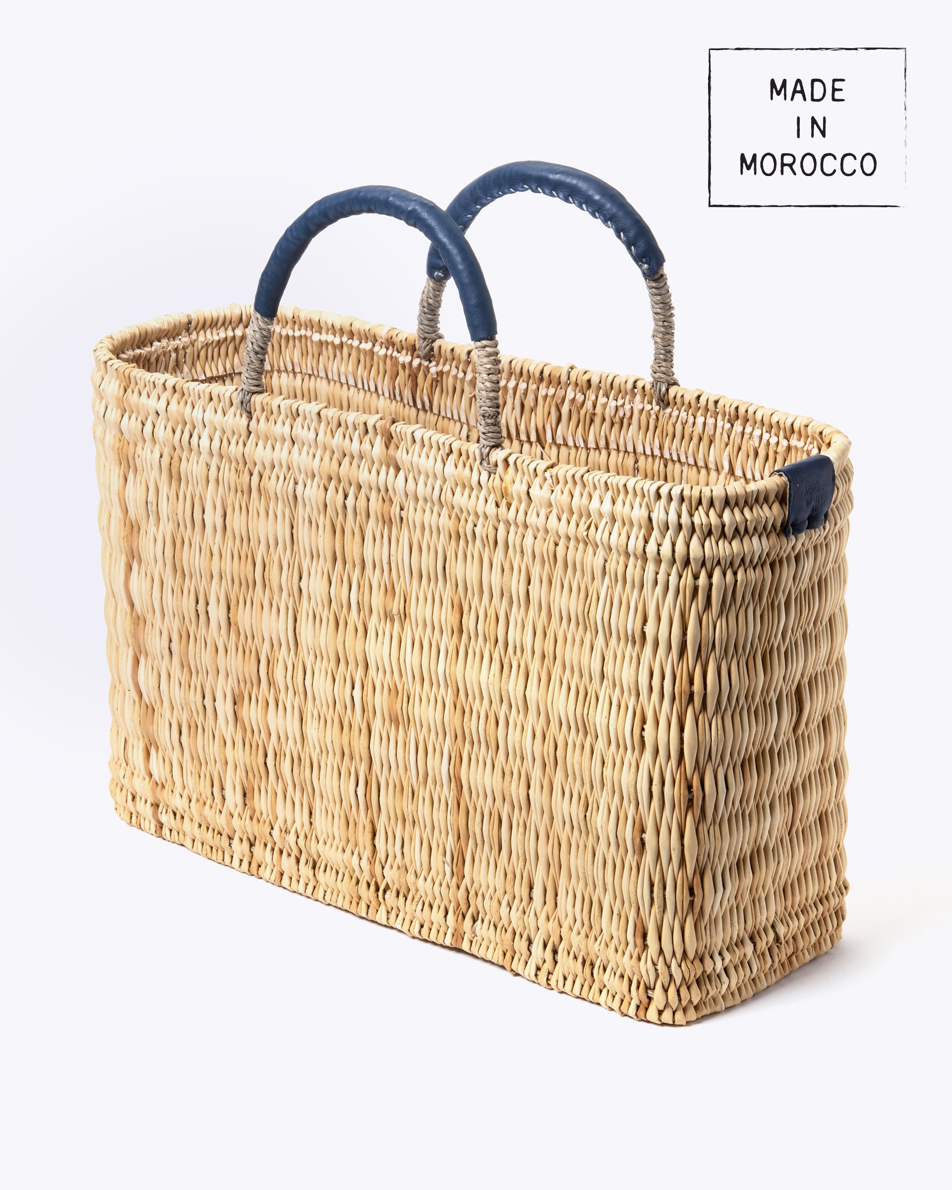 medium straw basket wrapped with dark blue leather handle on a white background at an angle