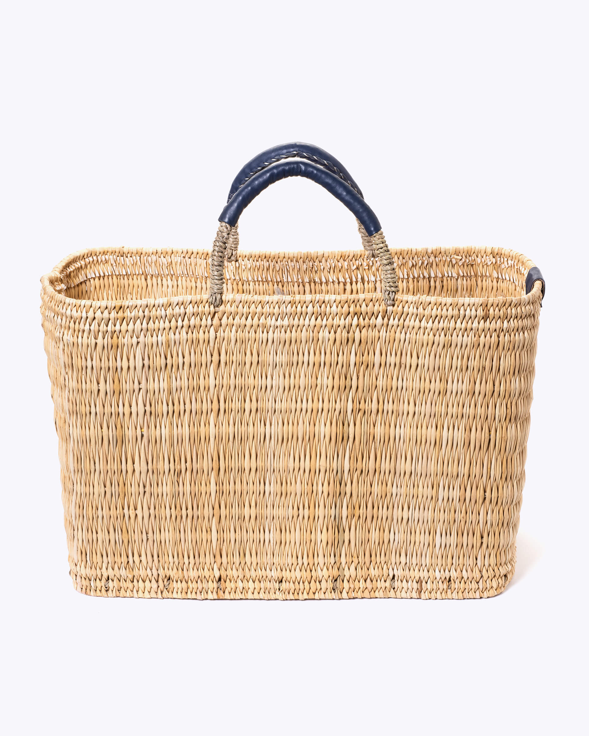 large straw basket wrapped with dark blue leather handle on a white background