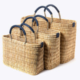 small, medium, large straw basket wrapped with dark blue leather handles on white background