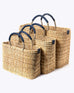 small, medium, large straw basket wrapped with dark blue leather handles on white background