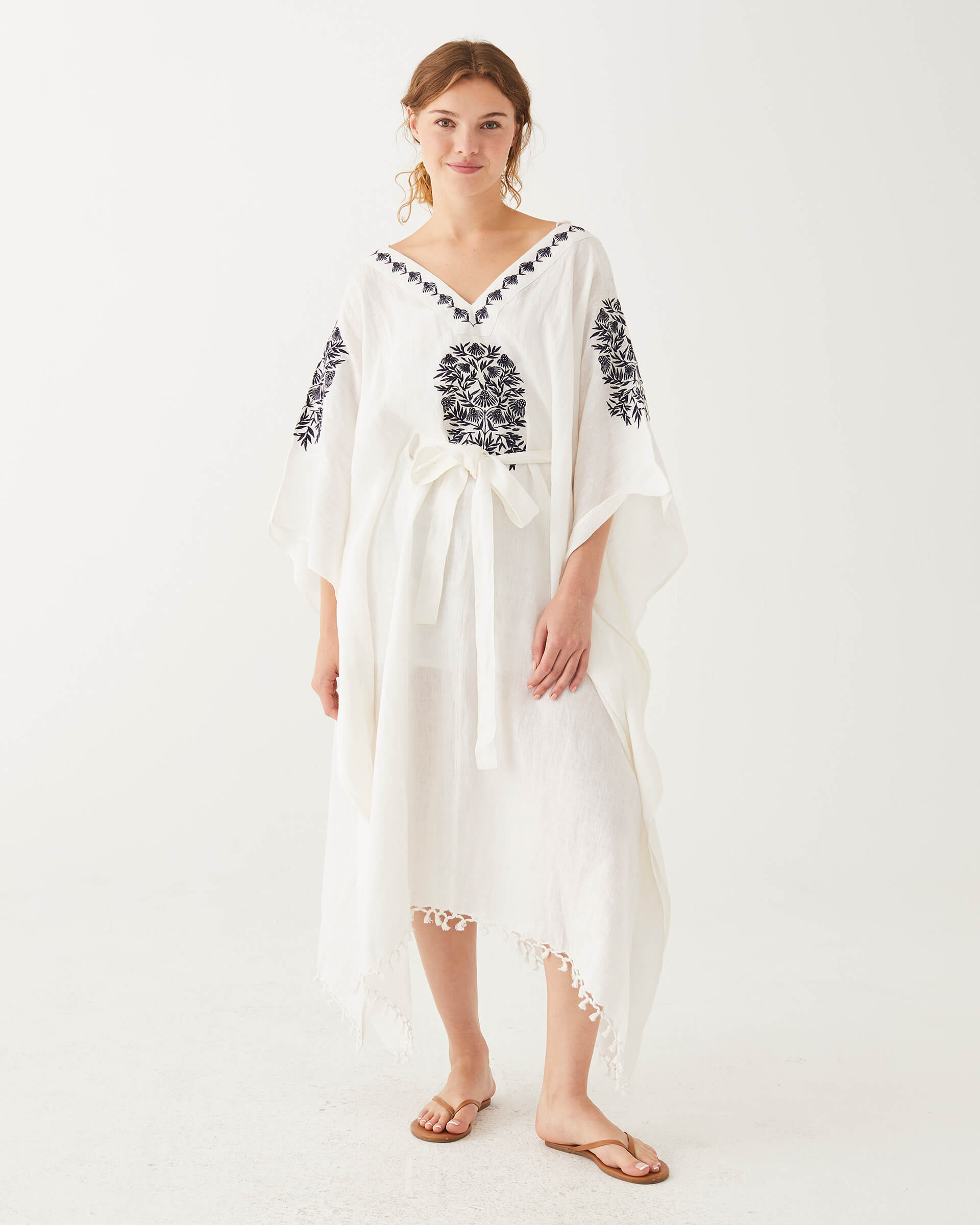 female wearing white and blue embroidered kaftan with v-neck and belt on a white background