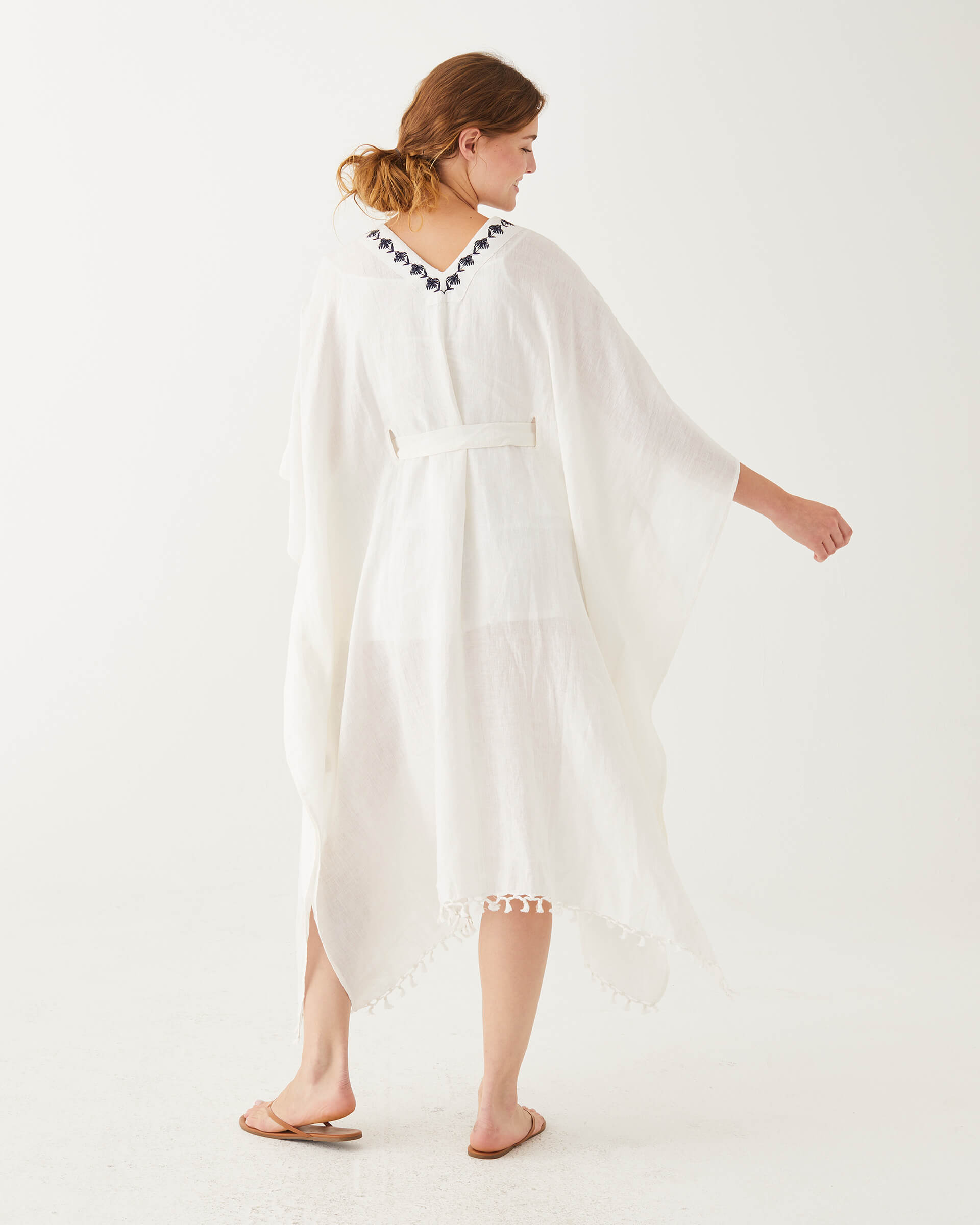 female wearing white and blue embroidered kaftan with v-neck and belt backwards on white background