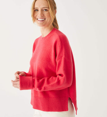 female wearing red crewneck sweater standing slightly to the side in front of a white background