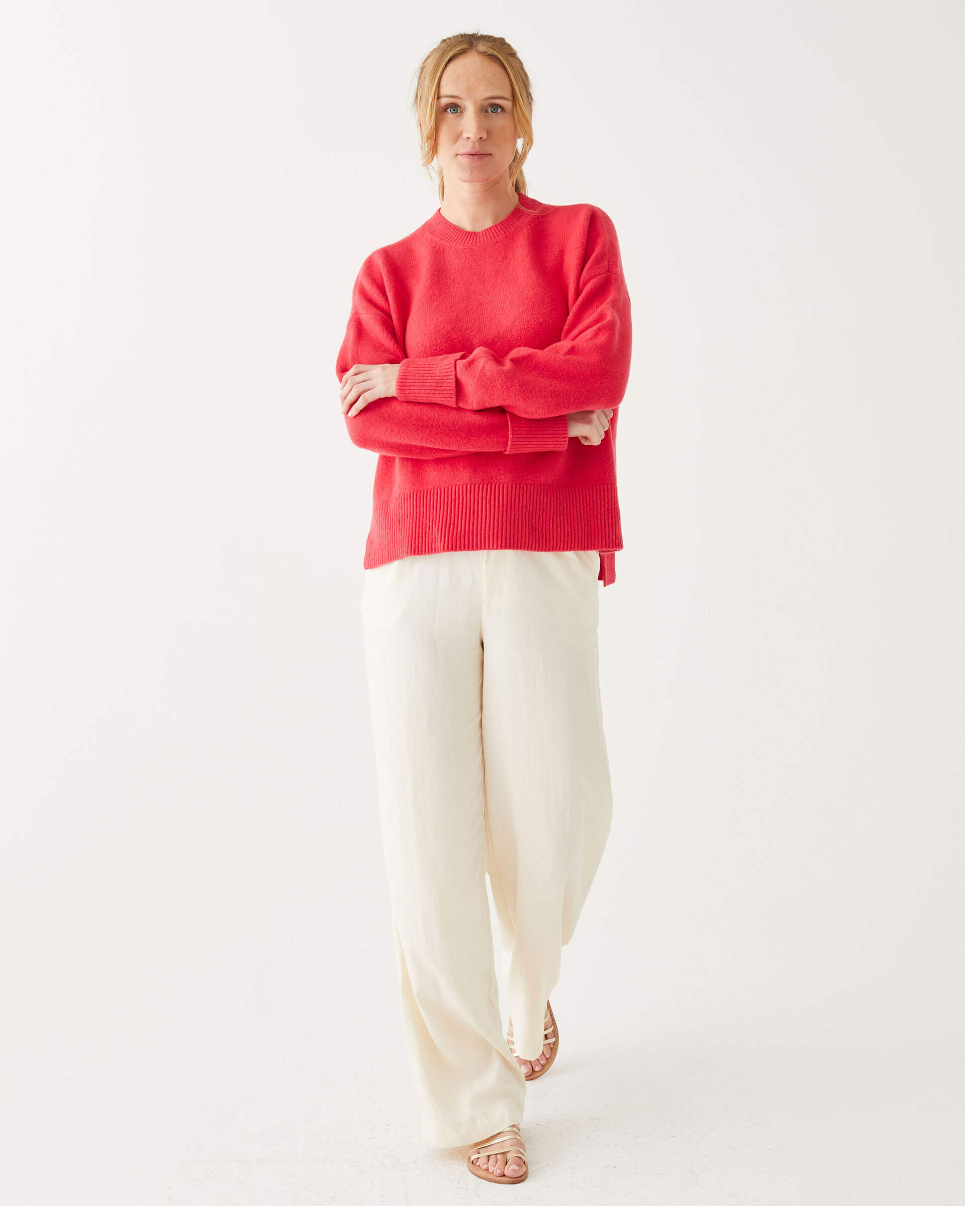 female wearing red crewneck sweater standing arms crossed in front of a white background