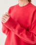 close up on the sleeve turnback cuffs of female wearing red crewneck sweater on a white background
