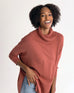 woman wearing mersea newport sweater in sienna color with a split front turtleneck and ribbed sleeves.