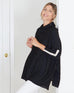 woman wearing mersea newport sweater in black with white accent stripe down lower sleeve  with a split front turtleneck and ribbed sleeves