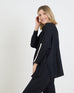 side view of woman wearing mersea newport sweater in black with white accent stripe down lower sleeve with a split front turtleneck and ribbed sleeves