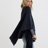 female wearing light black wrap over her shoulders standing sideways on a white background 
