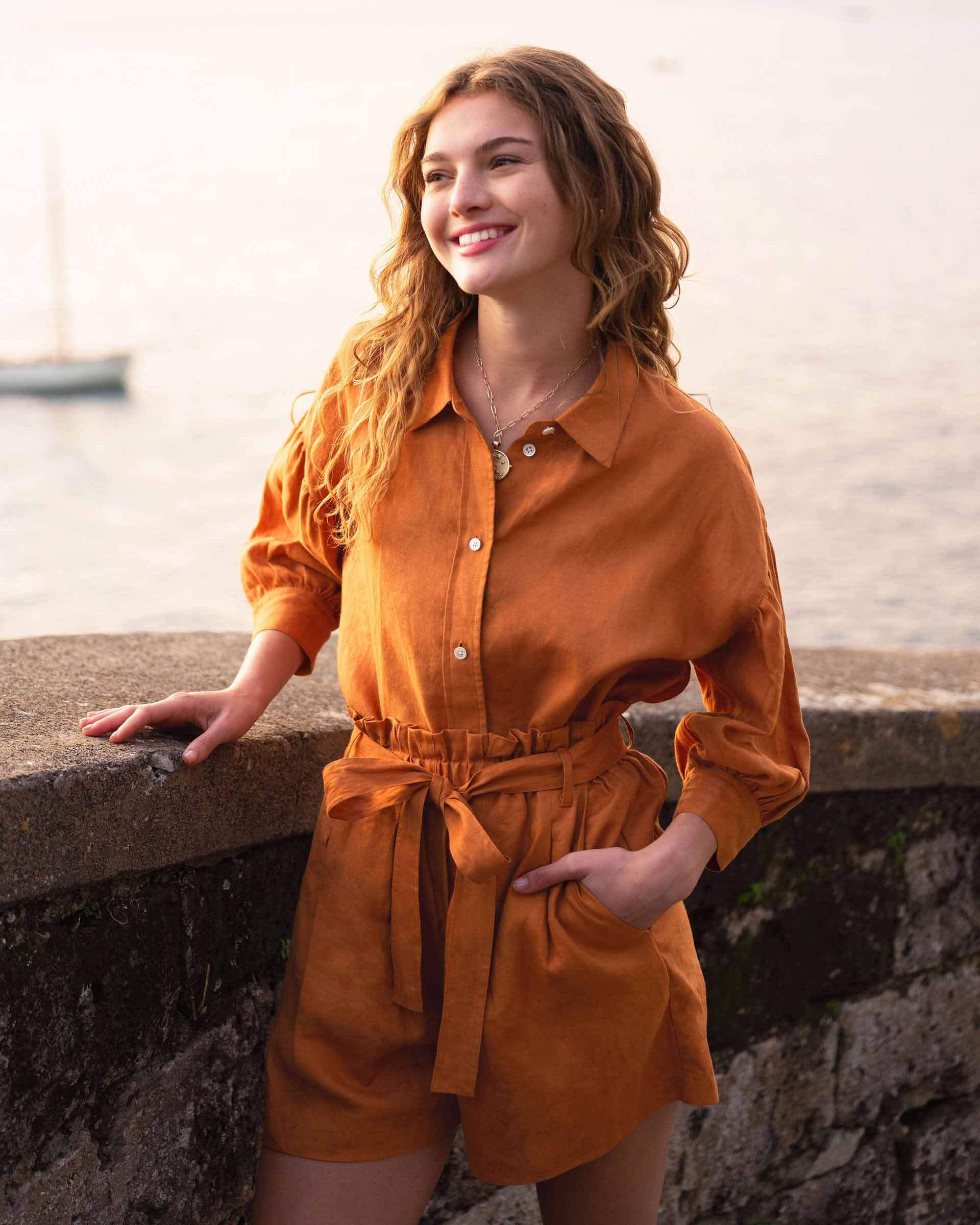 female wearing clay linen shirt with button-down, collar, and matching shorts near the ocean 