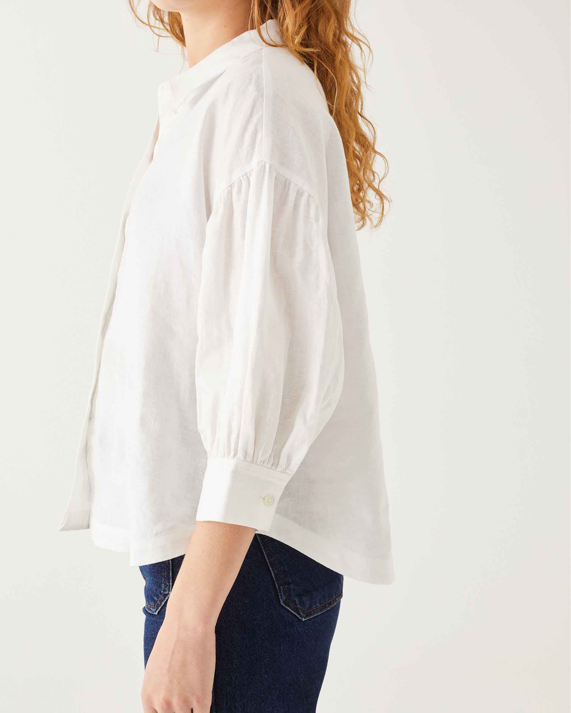 side detail of female wearing white linen shirt with button-down and collar on white background