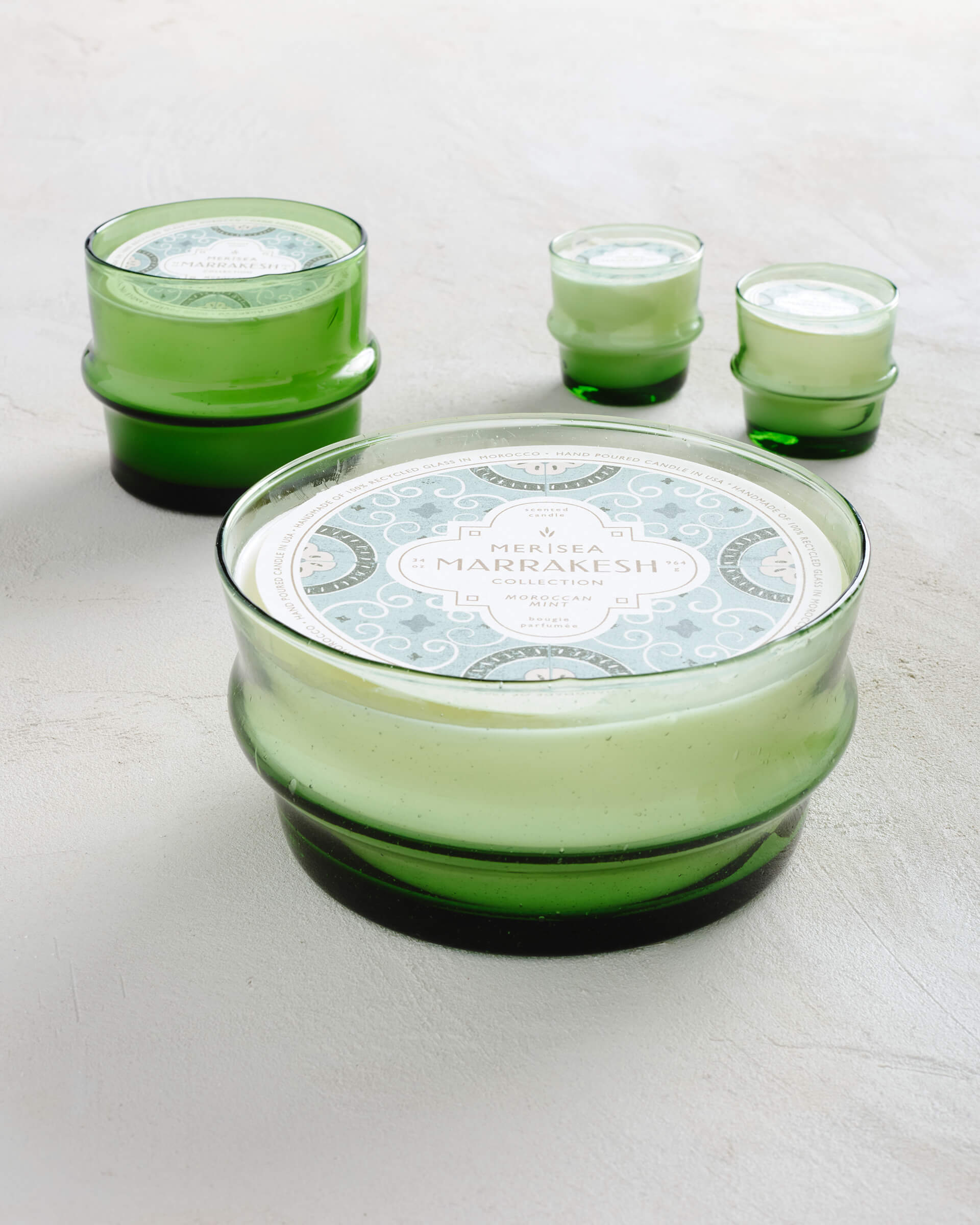 green glass Moroccan Mint candle bowl sitting near short and tall glass candles on white background