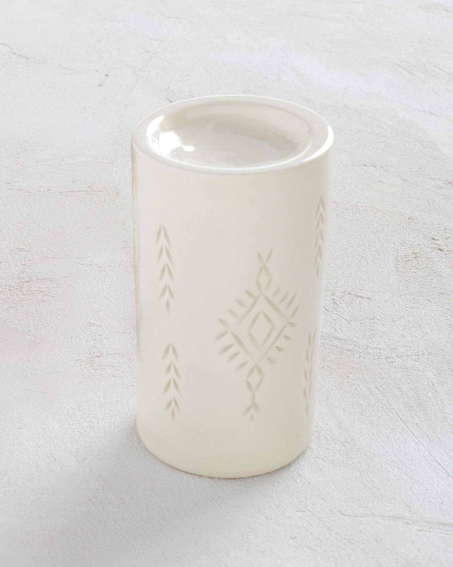 white ceramic scented oil burner with beautiful designs sitting on a white background 