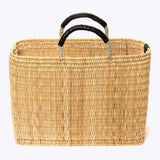 large straw basket wrapped with black leather handle on a white background 