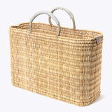 large straw basket wrapped with neutral leather handle on a white background at an angle