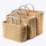 small, medium, large straw basket wrapped with neutral colored leather handles on white background