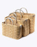 small, medium, large straw basket wrapped with neutral colored leather handles on white background