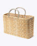 medium straw basket wrapped with neutral leather handle on a white background at an angle