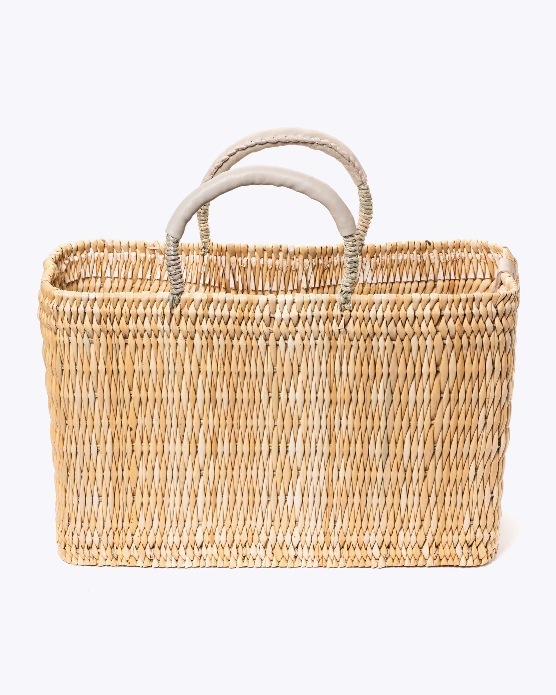medium straw basket wrapped with neutral leather handle on a white background 