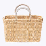 small straw basket wrapped with neutral colored leather handles on a white background