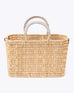 small straw basket wrapped with neutral colored leather handles on a white background