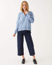 female wearing light blue collared v-neck sweater standing in front of a white background