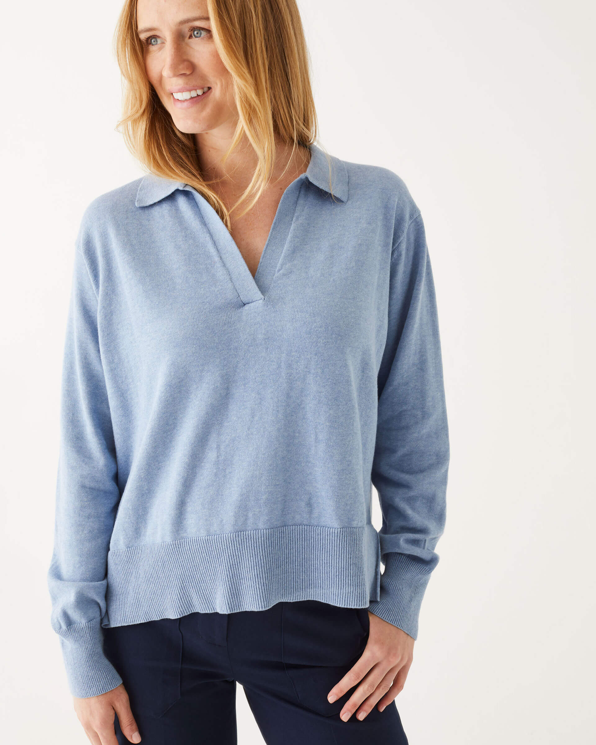 close up of female wearing light blue collared v-neck sweater in front of a white background