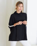 woman wearing mersea newport sweater in black with white accent stripe down lower sleeve with a split front turtleneck and ribbed sleeves