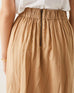 back detail of female wearing tan linen skirt with elastic back and zipper on a white background
