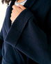 close up of female wearing navy wrap sweater with long cuffed ribbed sleeves on a white background