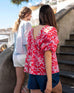 female wearing red top with pink floral print and puff sleeves walking up stairs with a friend