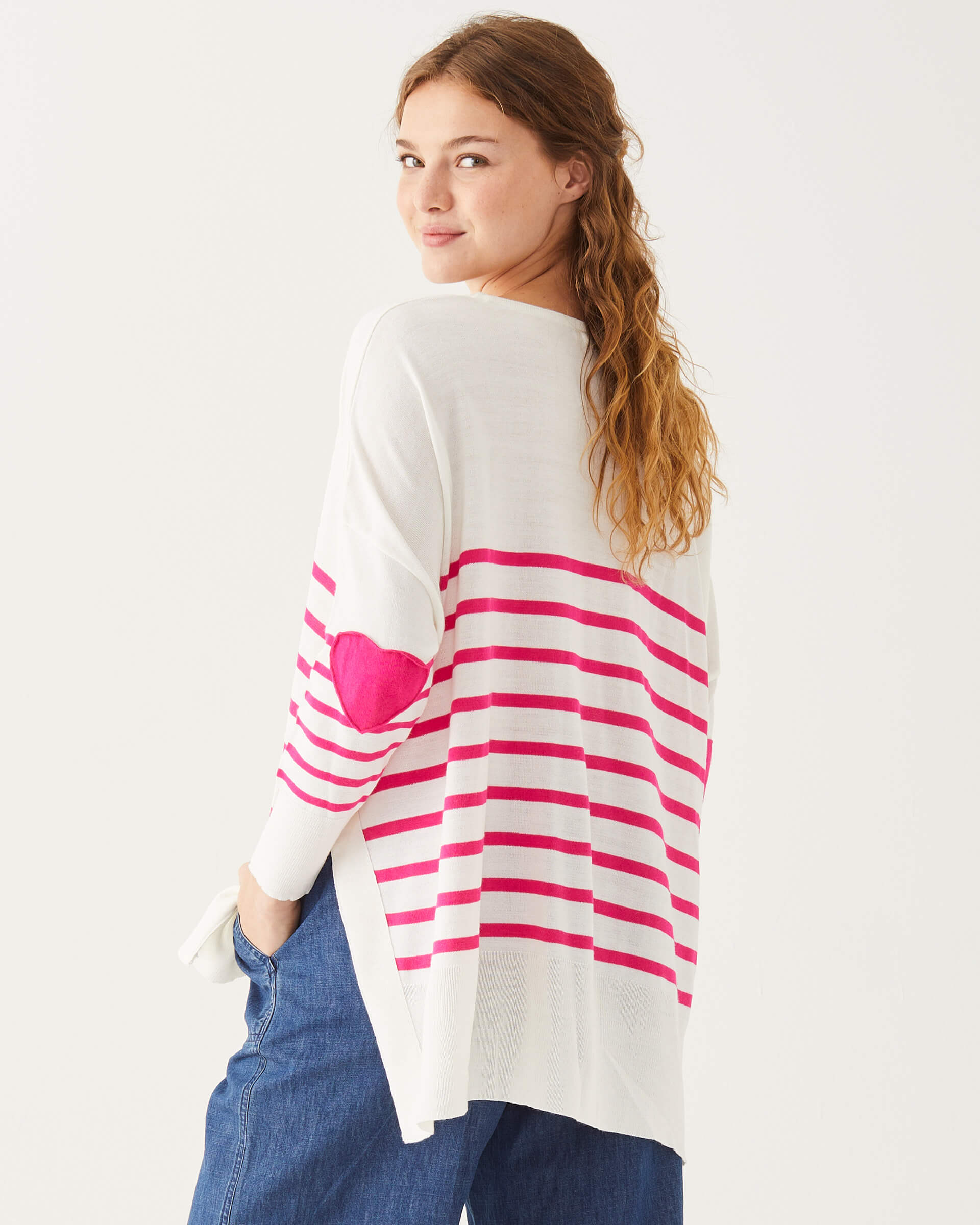 female wearing white and pink striped sweater with pink hearts on the elbow looking over shoulder