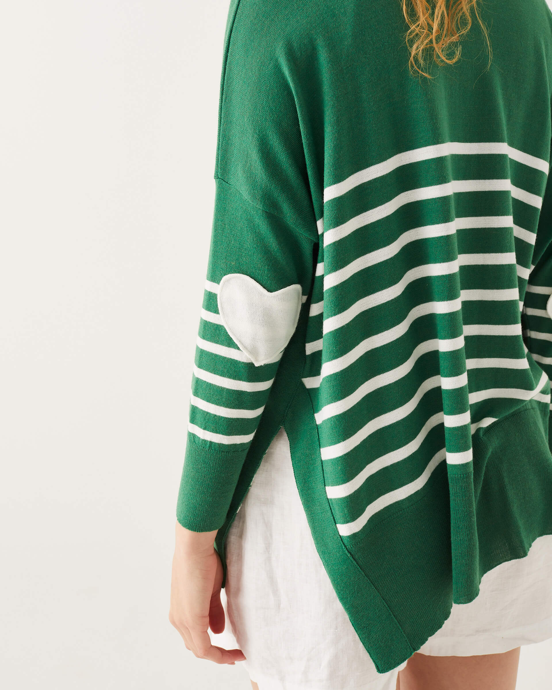 close up of green and white striped sweater with white heart on the elbow and split sides