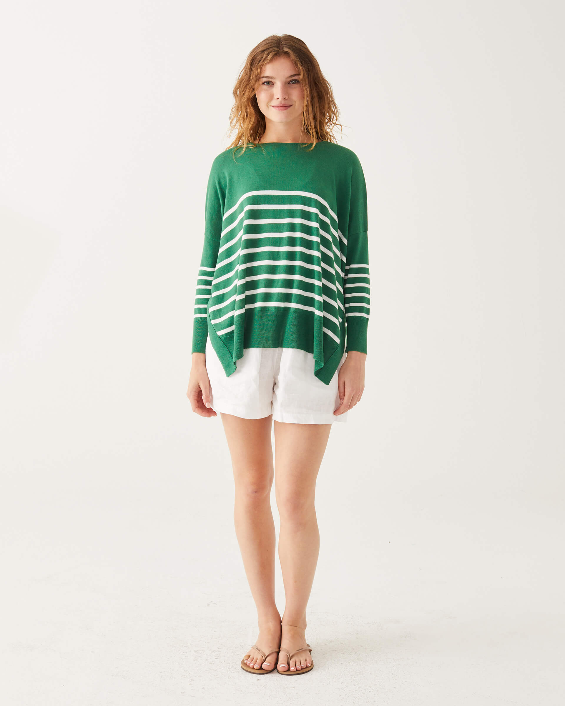 female wearing green and white striped sweater standing on a white background 