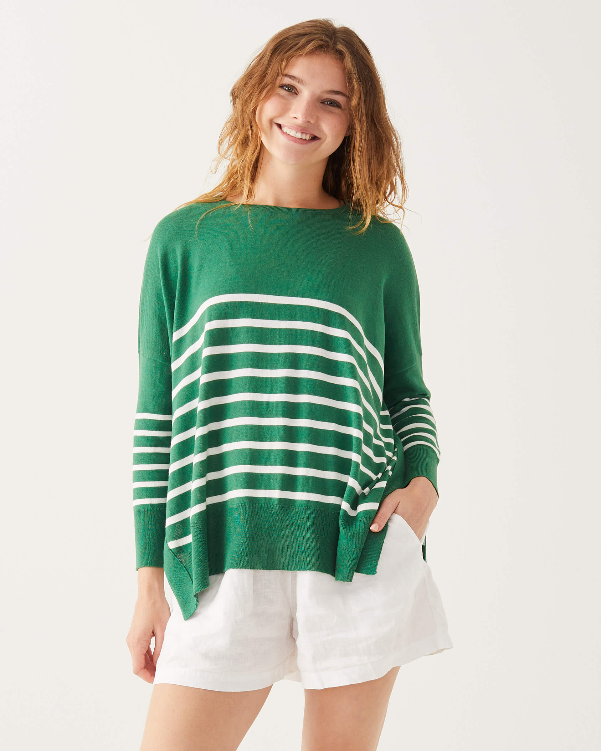 female wearing green and white striped sweater standing on a white background 