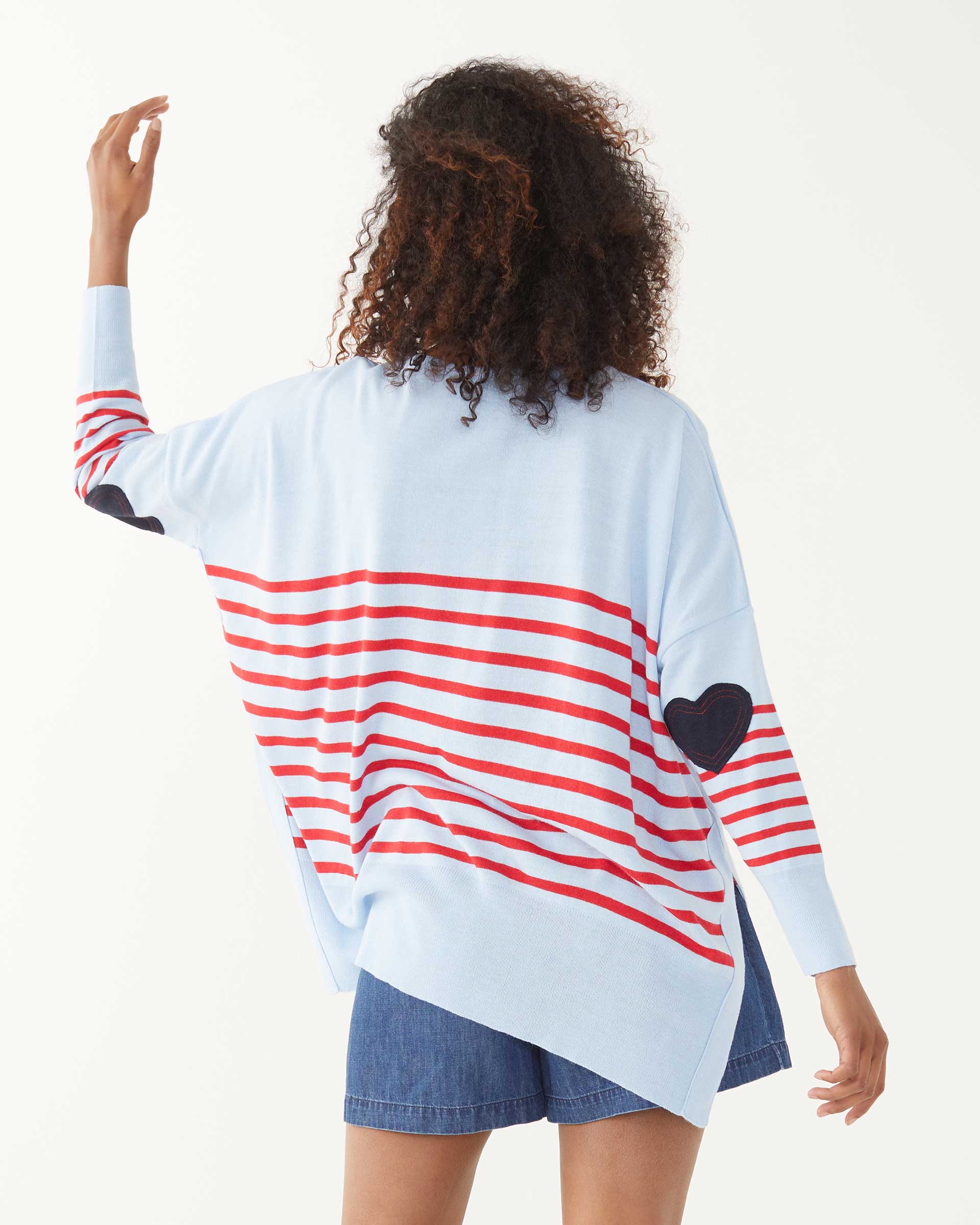 female wearing blue and red striped sweater backward with a heart elbow patch on a white background