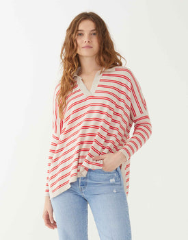 female wearing red and sand striped polo sweater with side slits hand in pocket on white background