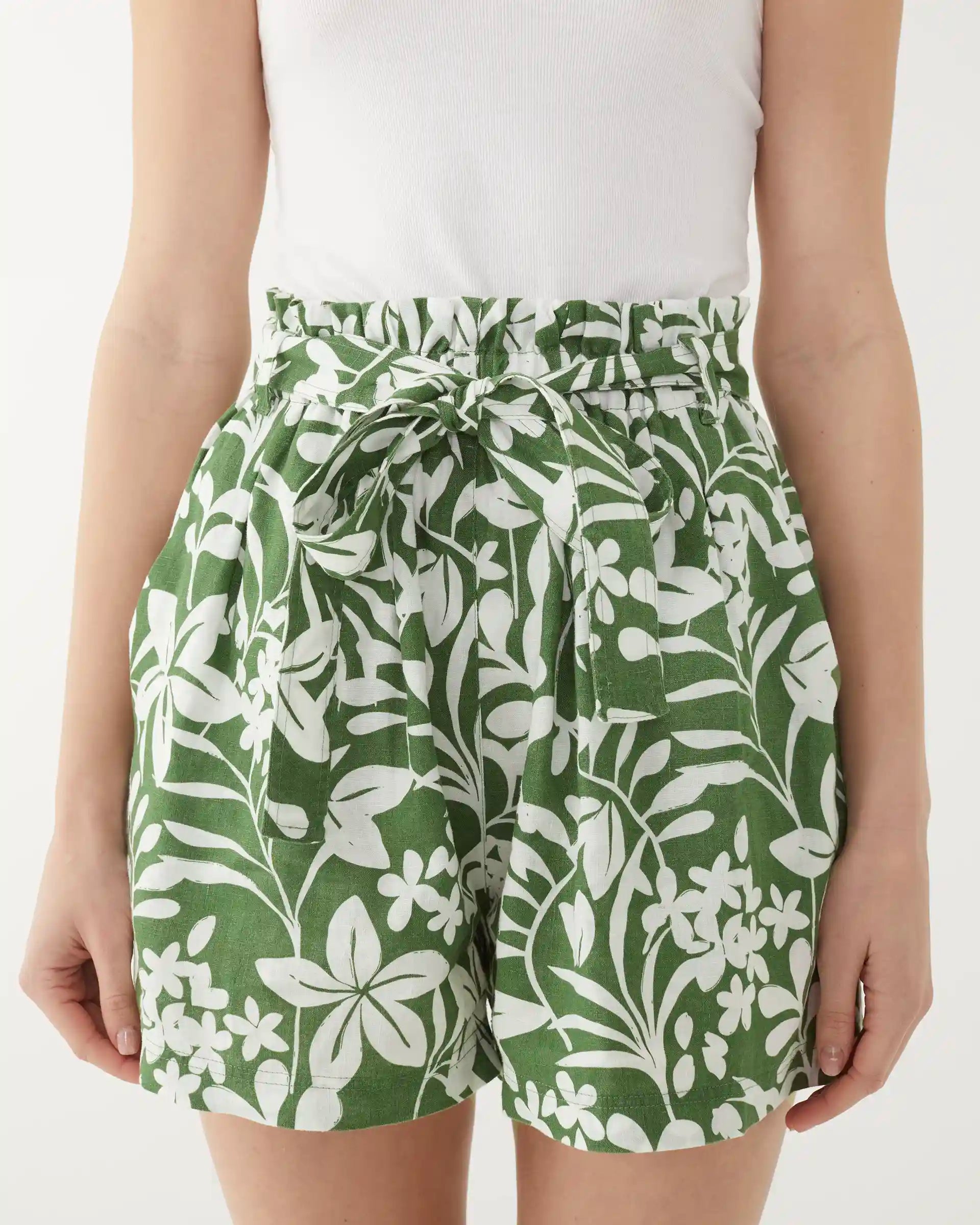 close up female wearing green linen shorts with white floral print on a white background