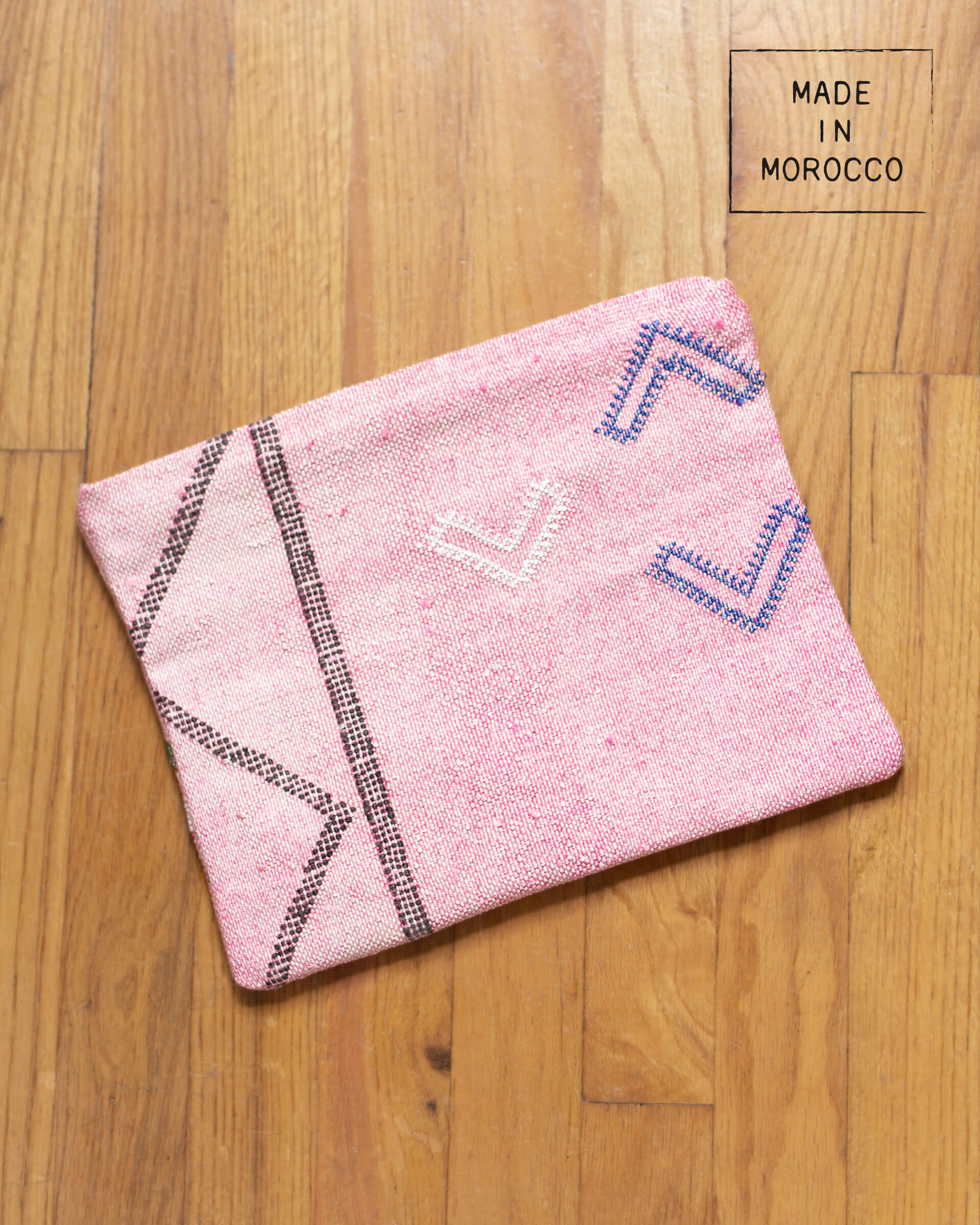 pink cactus silk clutch with design laying on brown wooden floor made in morocco