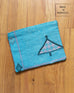 turquoise blue cactus silk clutch with design laying on brown wooden floor made in morocco