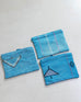 three turquoise blue cactus silk clutches with designs laying on a white floor
