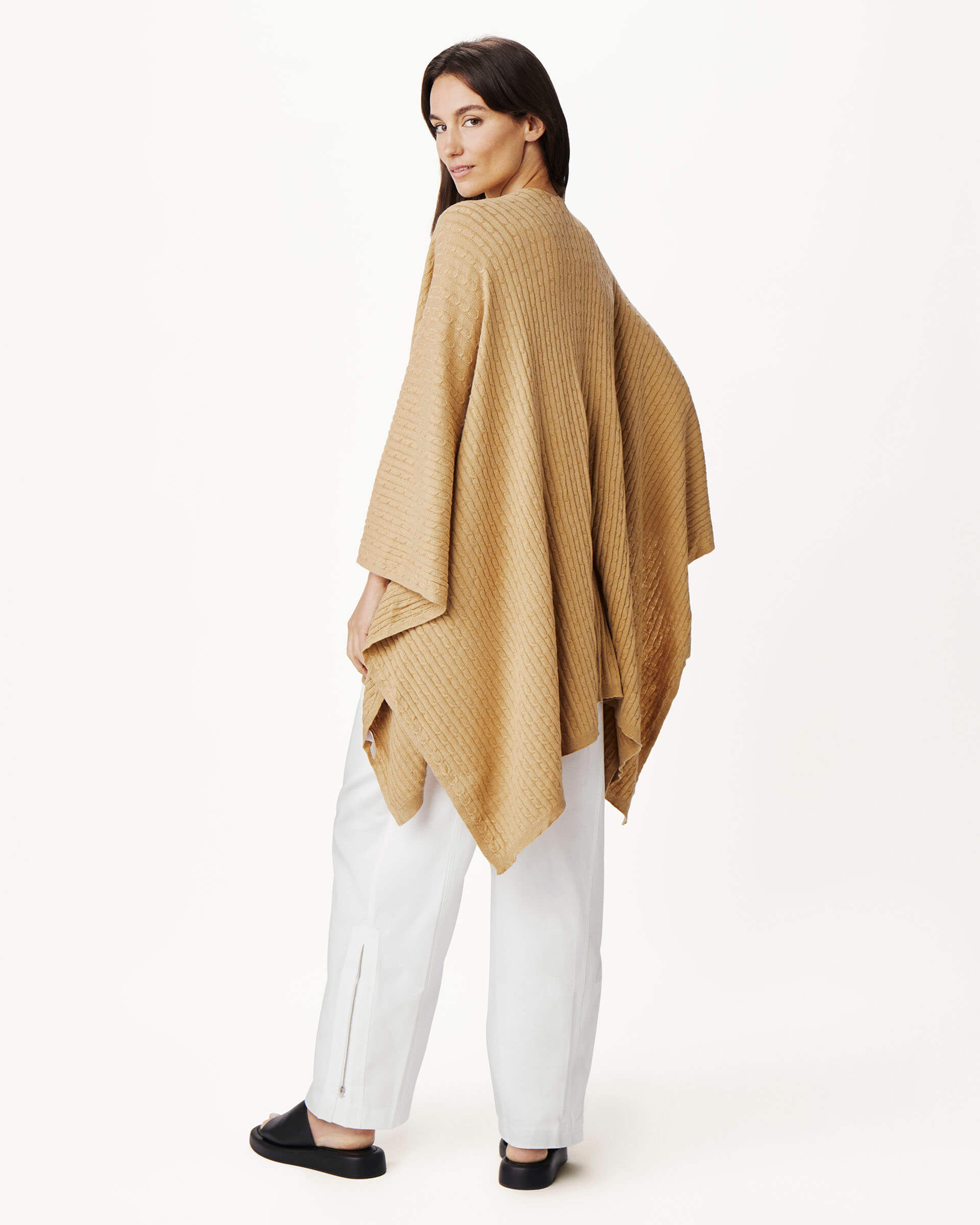 female wearing golden brown cable knit wrap turned around on a white background