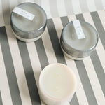 three 7 oz grey saltaire canister candles on a grey and white striped background