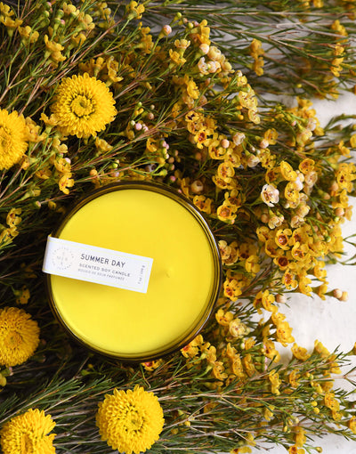 7 oz yellow summer day canister candle surrounded by a bunch of yellow flowers 