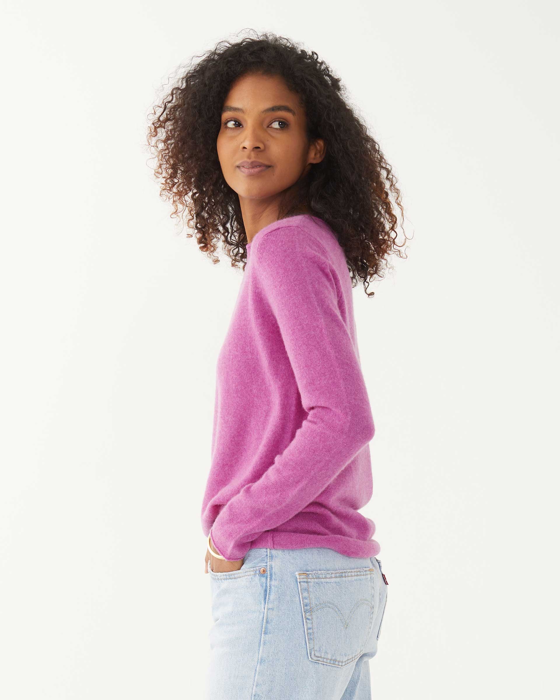 female wearing purple fitted cashmere sweater with a crewneck sideways on a white background